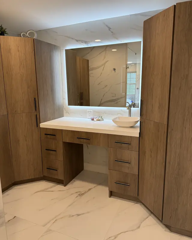 Primary bathroom with a tall walnut-look cabinet, makeup vanity and backlit mirror