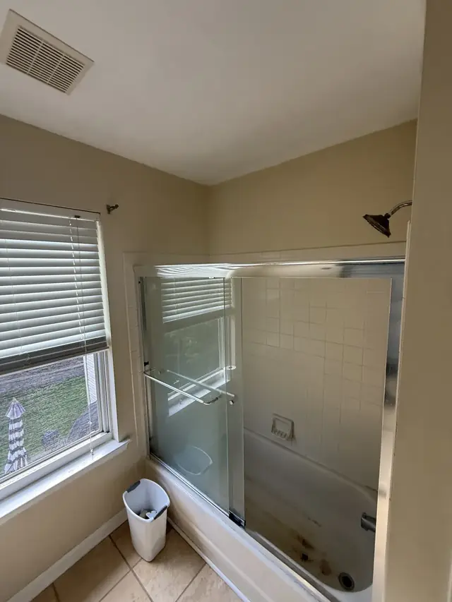 Before: beige bathroom with an alcove tub and a framed sliding shower door
