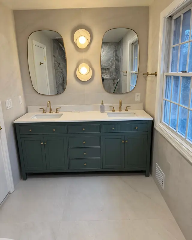 Green double vanity with round mirrors and brass sconces