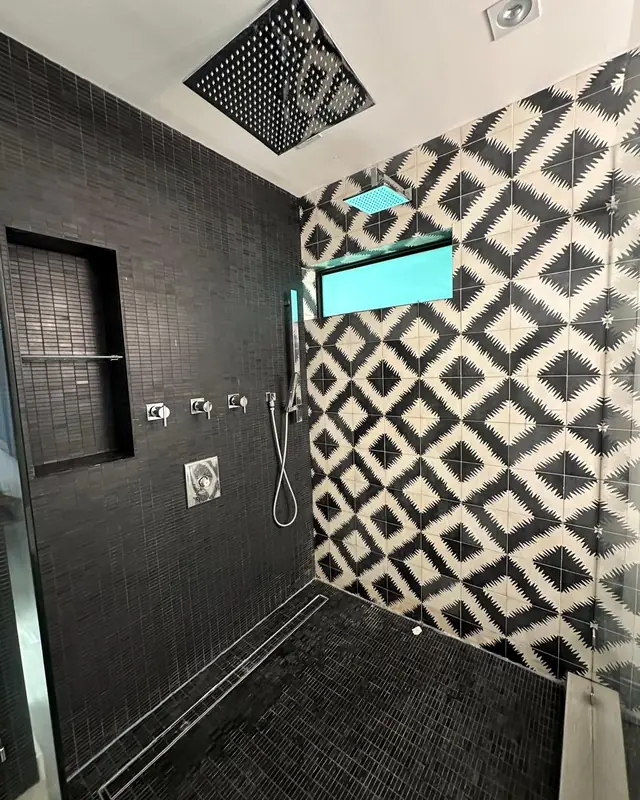 Black and white patterned tile shower with a linear drain