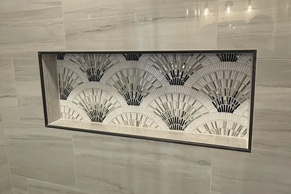 Shower niche lined with a fan-pattern mosaic, framed by a thin matte black edge