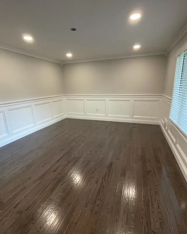 Wide room finished with dark plank flooring and wainscoting