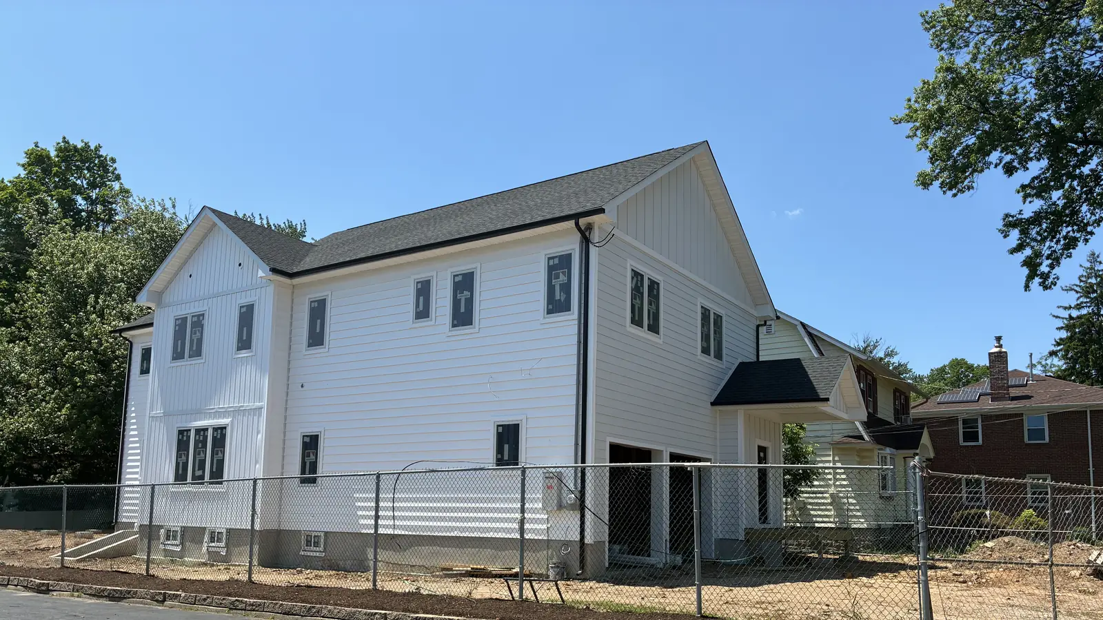 New two-story home with white board-and-batten siding built by GUS SKYY