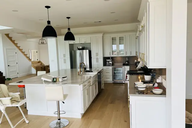 Open kitchen with white cabinets, a quartz island with seating and wood floors