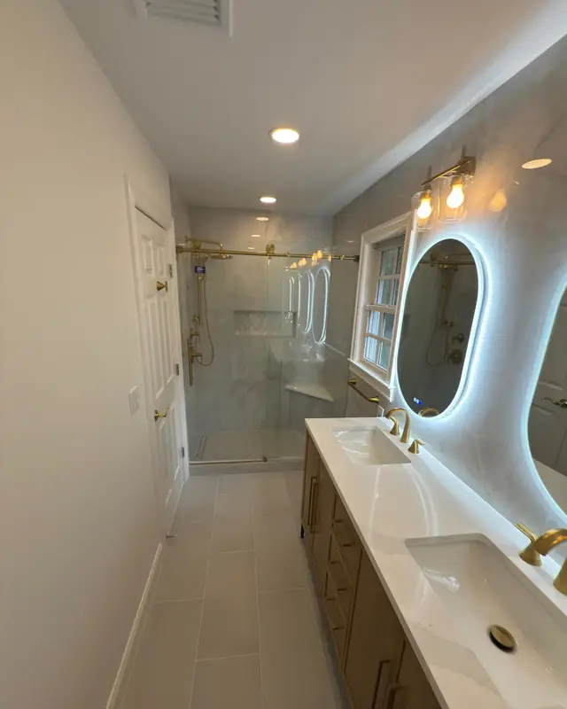 Primary bathroom in Franklin Lakes with a gold shower column, niche and large-format marble-look tile