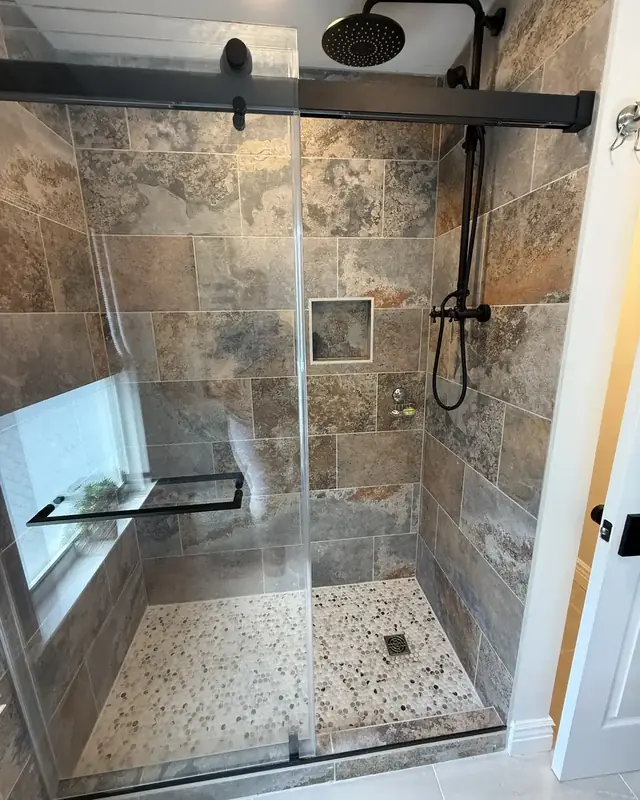 Walk-in shower with slate-look tile, a window and a pebble floor