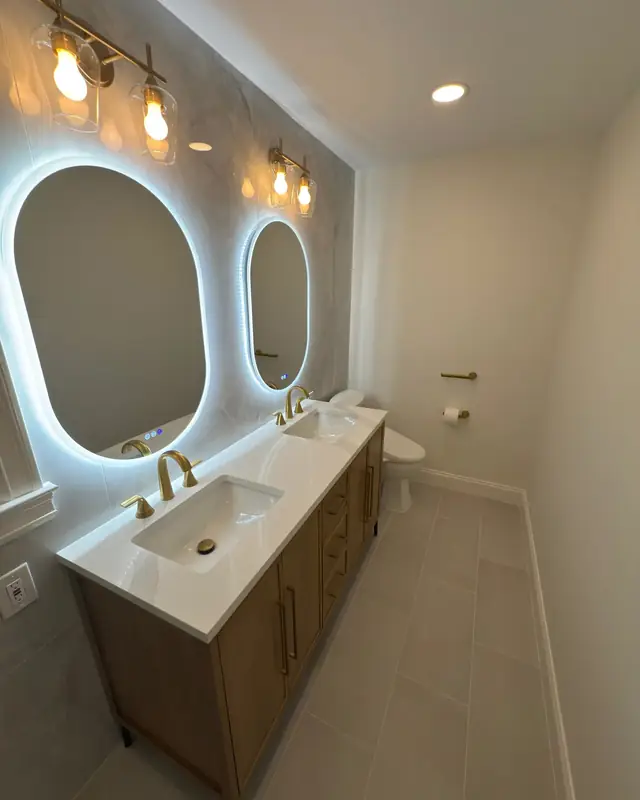 Oak double vanity with LED mirrors and brushed gold faucets