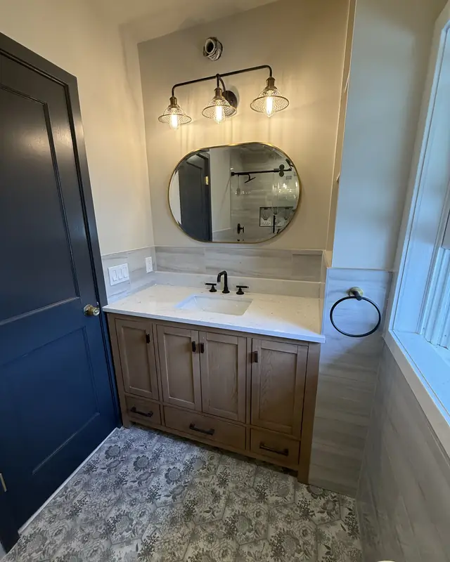 Oak vanity with a round brass mirror on a black-and-white patterned floor