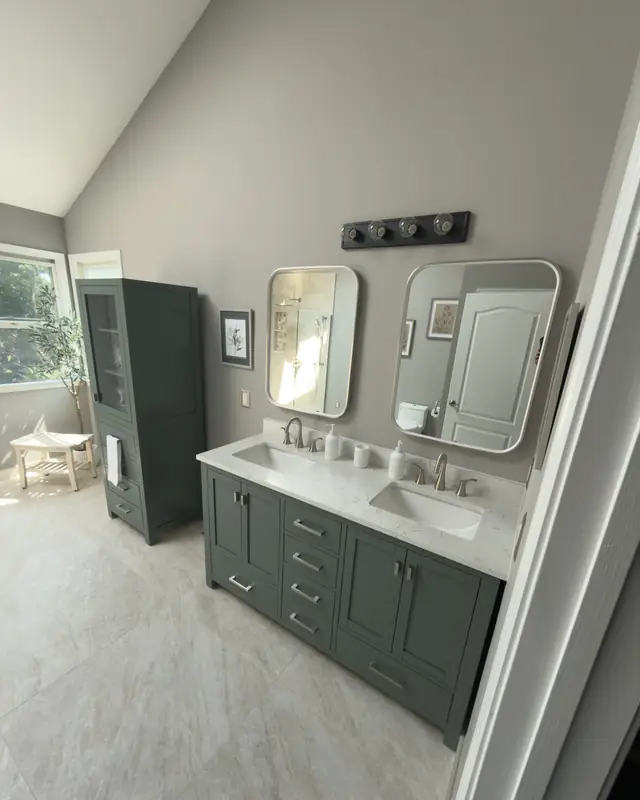 Green double vanity with white top, two mirrors and a four-light fixture