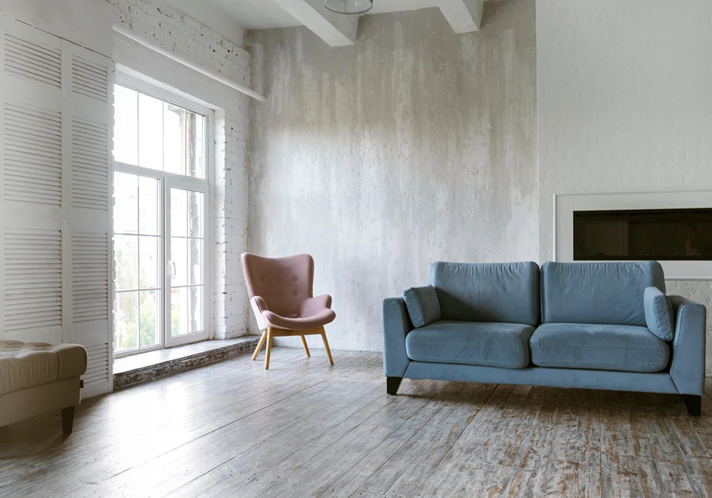 A living room with a light, bright floor and a blue sofa in the background